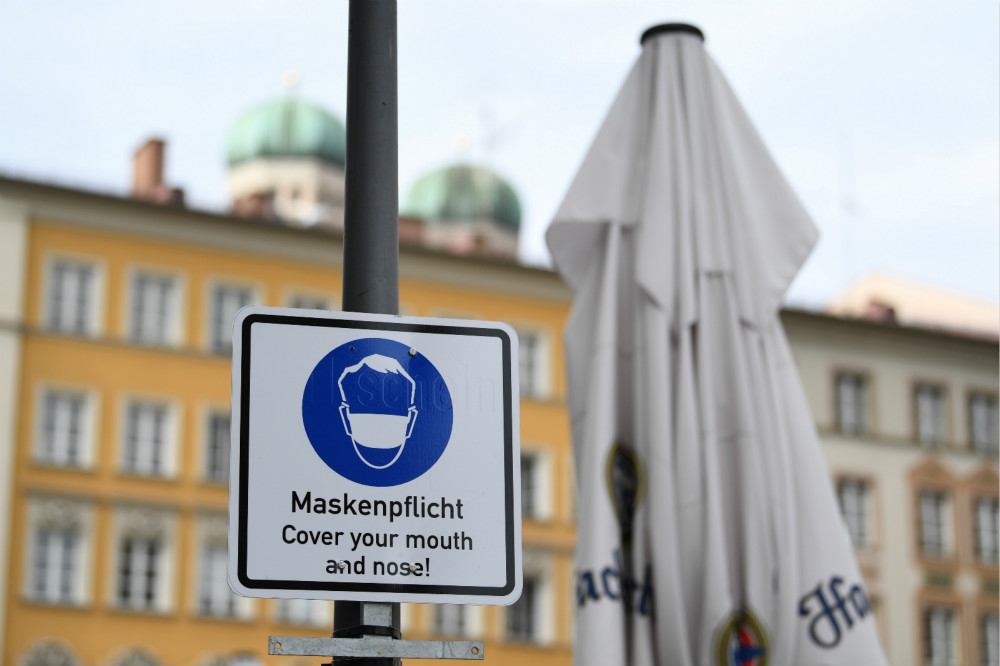 德國慕尼黑街頭提醒民眾戴上口罩防疫的告示牌。（湯森路透）