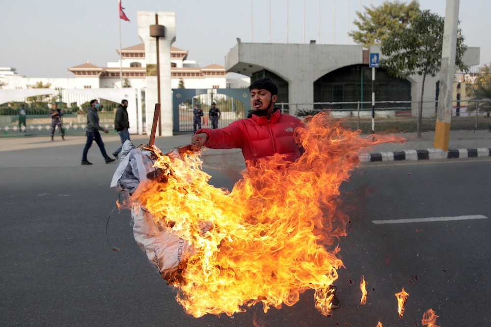總理奧利提議解散國會後，一名示威者在國會外焚燒他的肖像。（湯森路透）