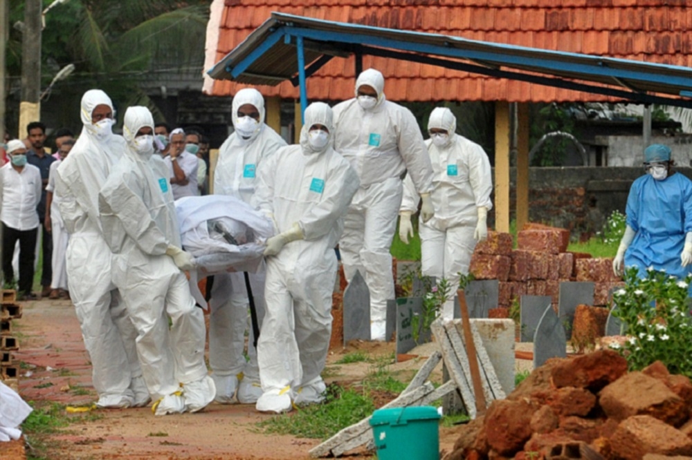 印度一群穿戴防護衣的醫護人員正在清理因感染尼帕病毒而死亡的人員。（湯森路透）