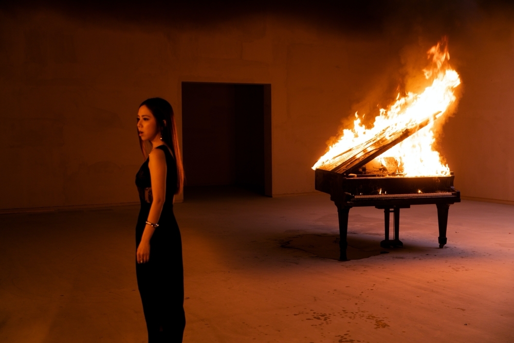 鄧紫棋拍攝新單曲〈孤獨〉MV，得靠近火燒鋼琴的場景對嘴演出。（索尼音樂提供）
