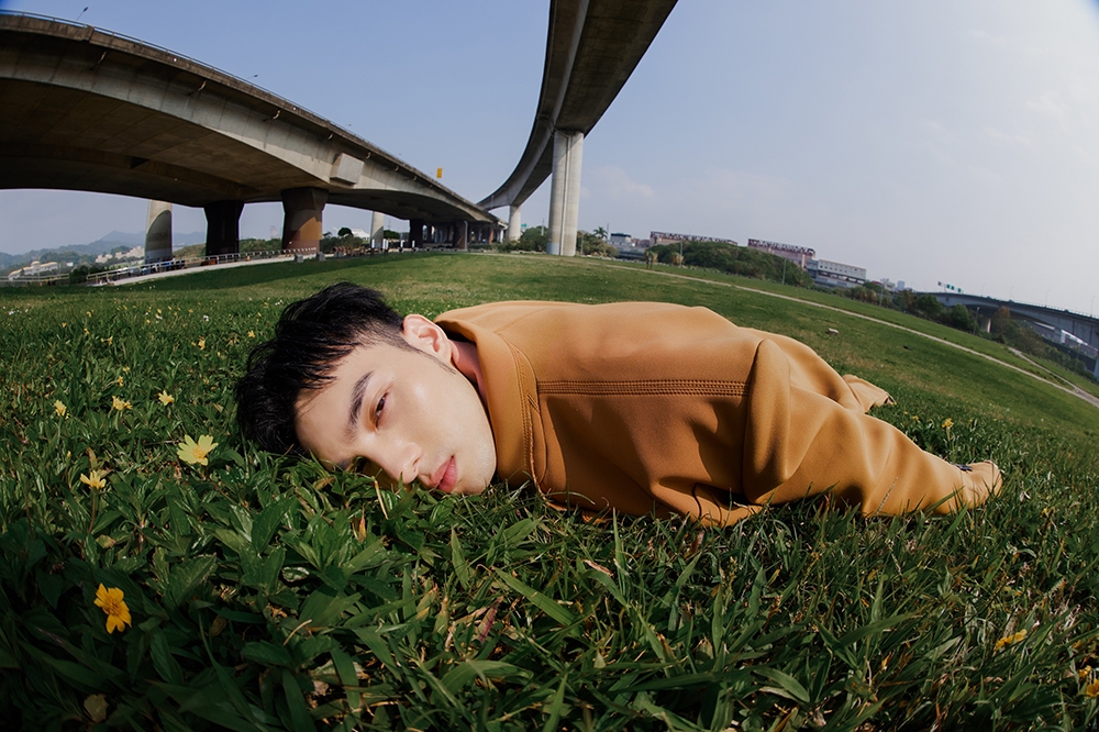 黃偉晉推出新單曲〈好累〉，拍照時兩眼微開緊趴草地，被蚊蟲叮咬到整個脖子過敏起紅疹。（愛貝克思提供）