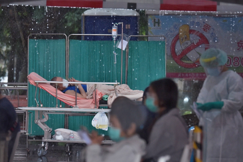 台北市聯合醫院忠孝院區，因急診空間不足，病患被暫時安置在急診室外的雨棚中，一名患者雙手合十緊握等待診治。（蔣銀珊攝）