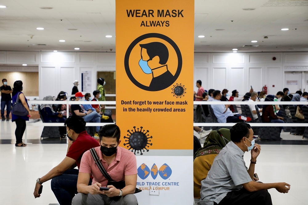 馬來西亞國內疫情吃緊，商場張貼告示、提醒民眾戴好口罩防疫。（湯森路透）