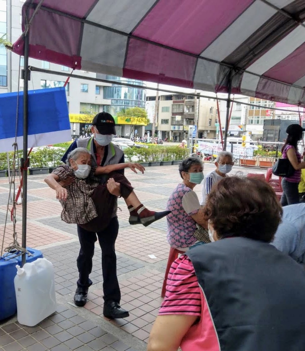 今(17)天台南市東區衛生所前一名96歲的阿嬤前往施打疫苗，下了車卻走不動，東區公所主任秘書陳俊達徵得家屬同意，將阿嬤「公主抱」進入衛生所，現場民眾也拍下這一張美麗的照片。(台南市政府提供)