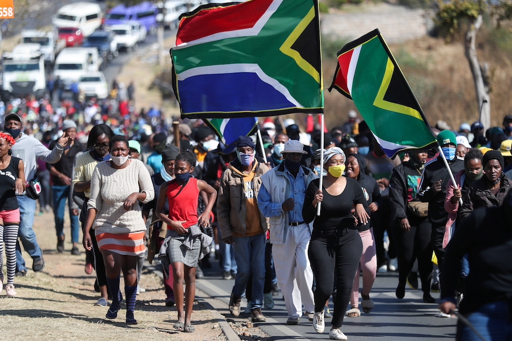非洲疫情重災國南非，將建立全球首座「mRNA技術轉移中心」，圖為疫情下南非索維托民眾上街抗議非法移民及當地犯罪問題畫面。（湯森路透）