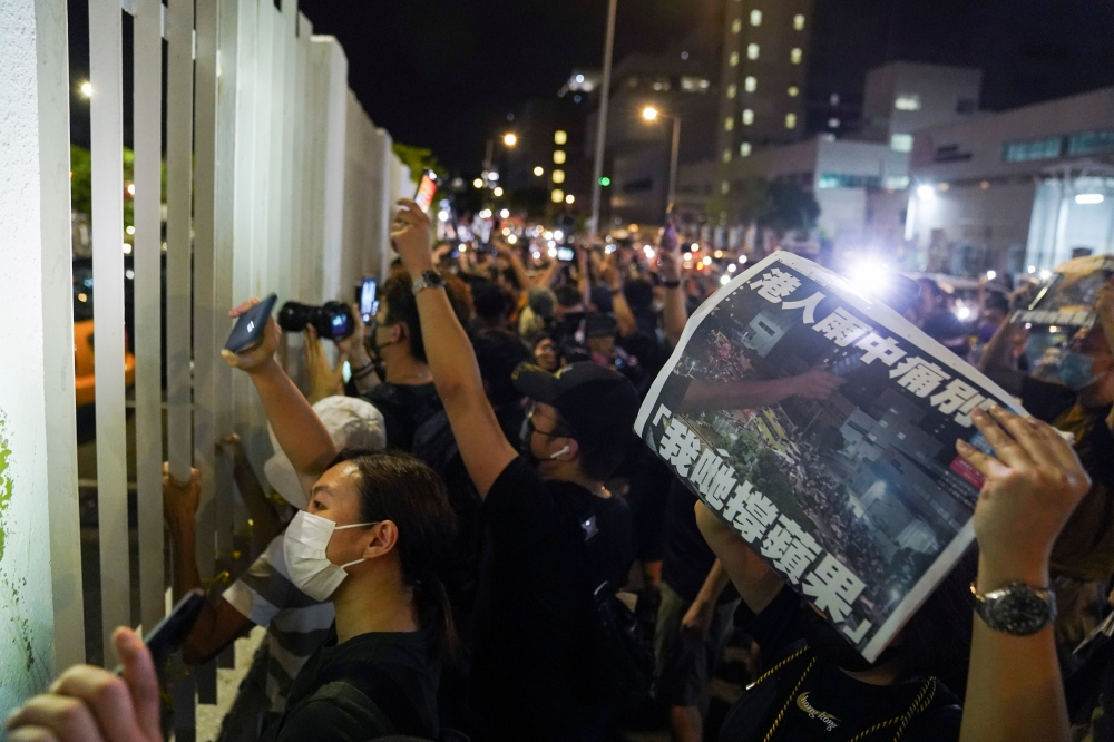 香港《蘋果日報》停刊，民進黨24日對此譴責中共扼殺香港民主自由。圖為民眾圍在港蘋大樓外拿著最後一份報紙，開手機燈光聲援。（湯森路透）