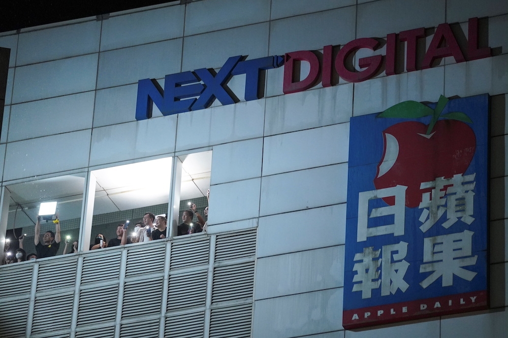 香港《蘋果日報》被迫停刊當天，大樓內員工與民眾以手機燈光互相致意。（湯森路透）