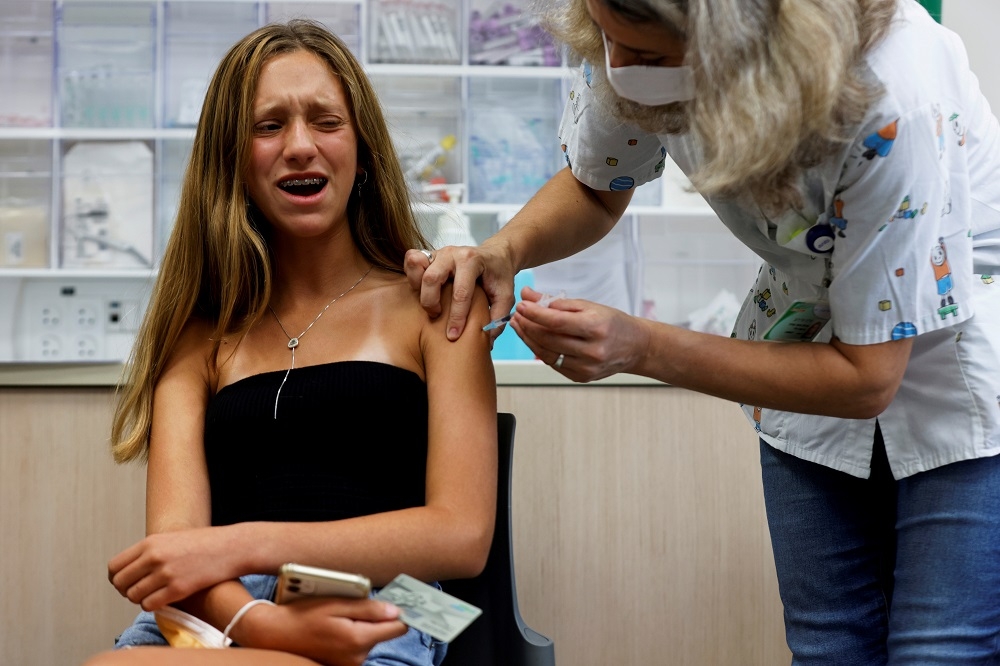 以色列醫護人員為民眾施打新冠疫苗。（湯森路透）