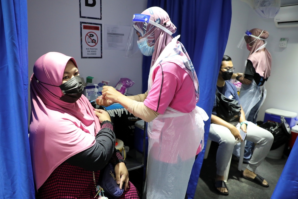 馬來西亞醫護替民眾接種新冠疫苗。（湯森路透）