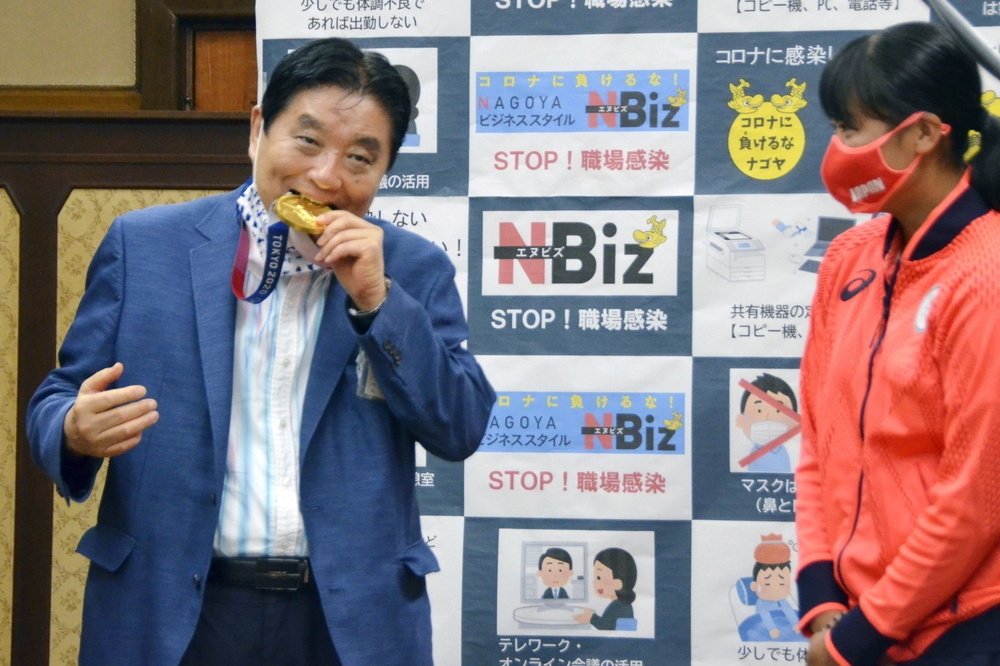 名古屋知事河村隆之（左）脫下口罩，在女壘選手後藤希友（右）咬著奧運金牌，遭到日本輿論砲轟。（湯森路透）