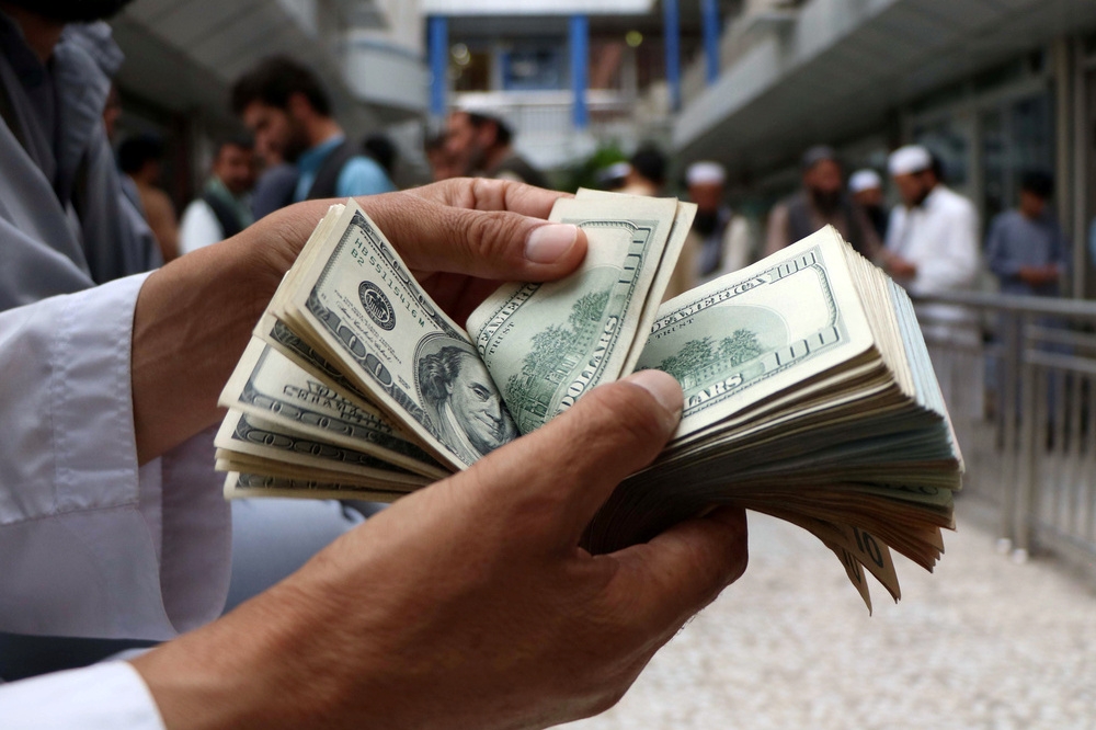 阿富汗商人點校手中的美元現鈔。（湯森路透）