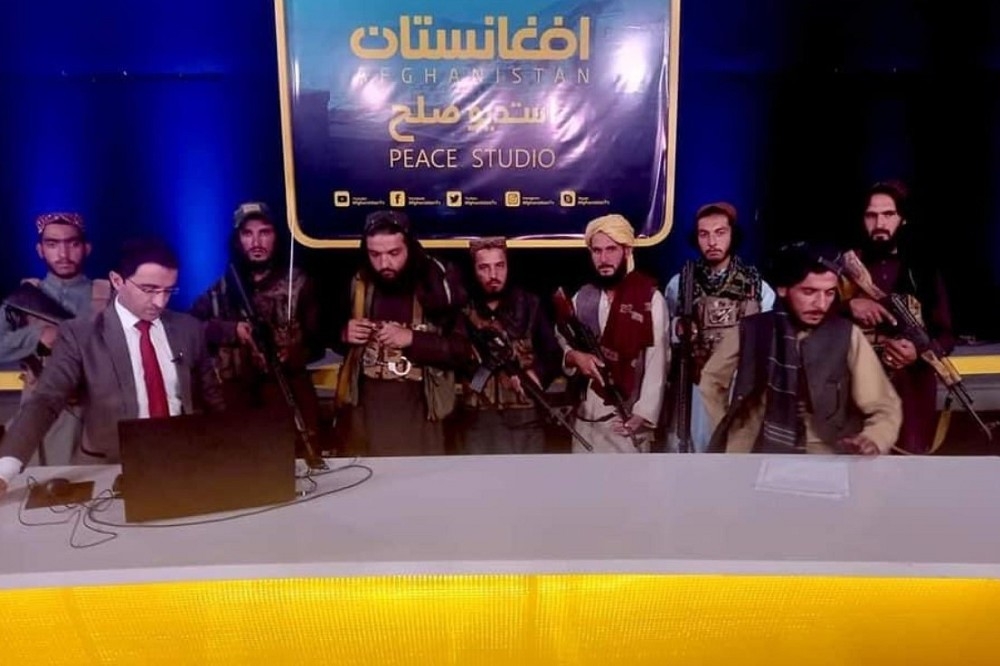 阿富汗政治辯論頻道主持人在一排神學士戰士陪同下播出。（推特截圖）
