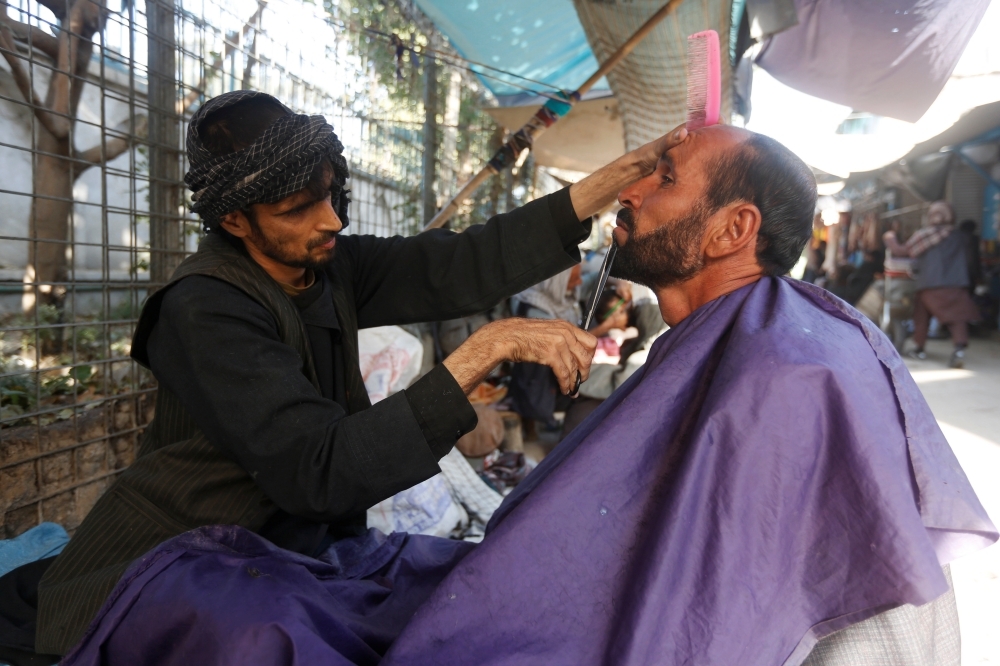 2017年，喀布爾的一名理髮師正為顧客修剪鬍子。（湯森路透）