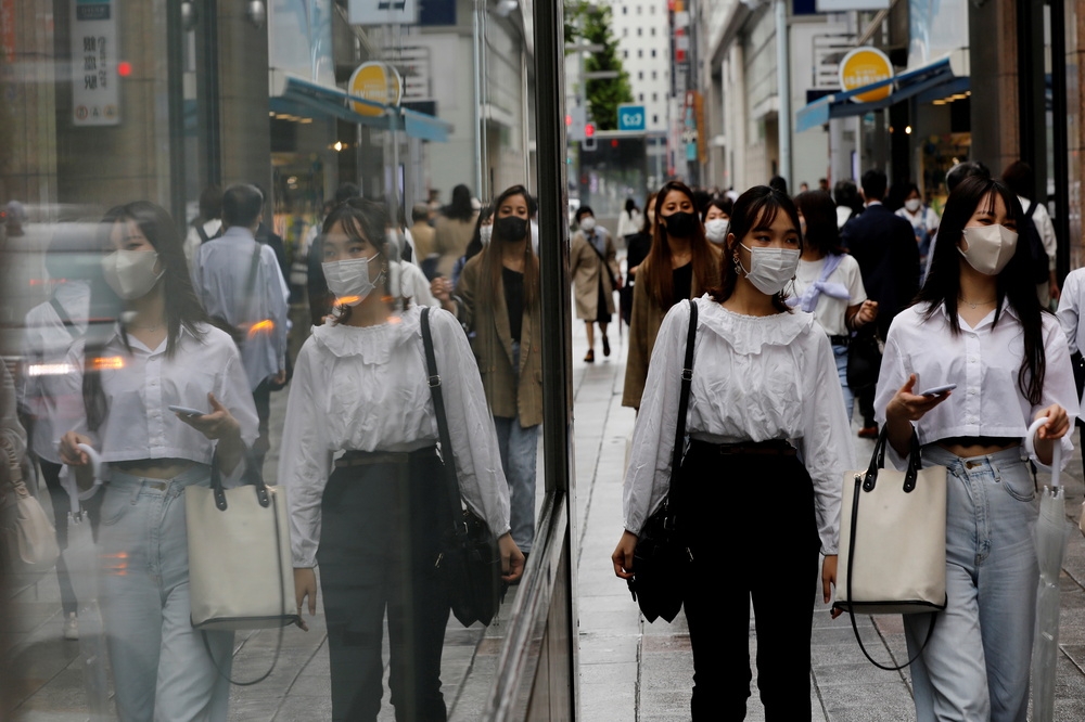 遵守防疫管制戴口罩上街的日本女性。（湯森路透）