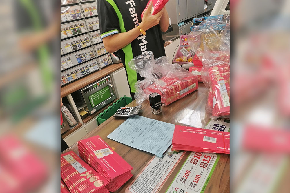 網友拍下超商櫃台上堆滿紙本五倍券，店員正忙著清點的畫面，引發熱議。（取自爆廢公社臉書）