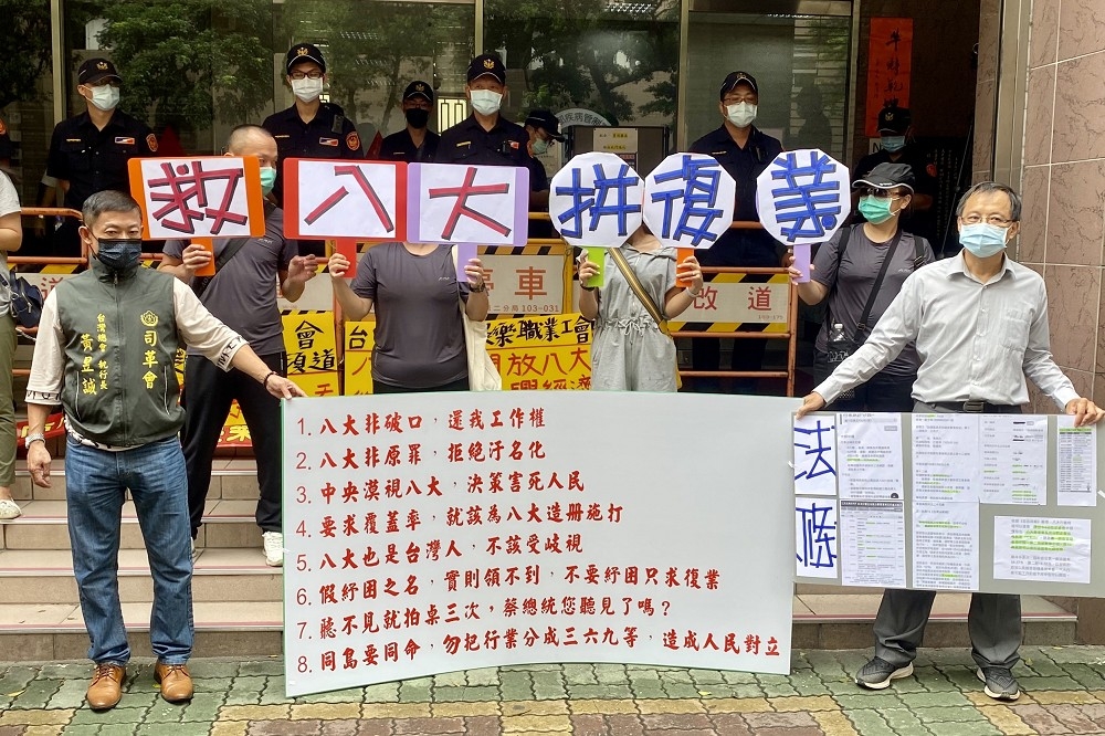 八大行業業者代表14日上午至中央流行指揮中心前舉布條抗議。（張哲偉攝)