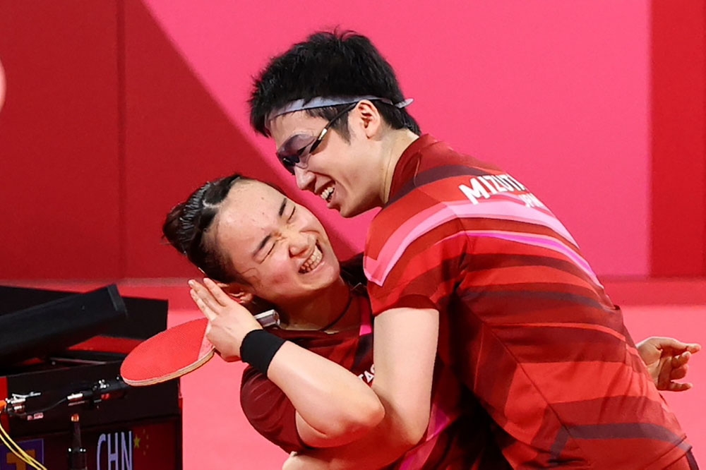 日本桌球選手伊藤美誠（左）與水谷隼在東奧男女混合雙打決賽奪金後，水谷隼開心的抱住伊藤美誠。（湯森路透資料照）