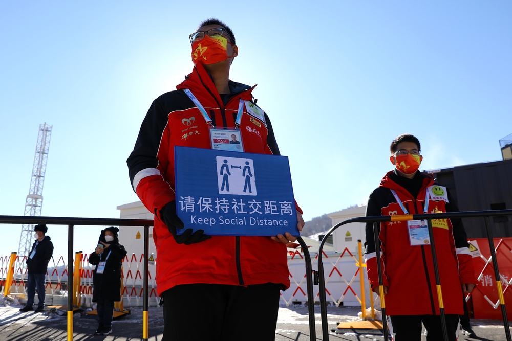 北京防疫人員在街頭提醒民眾「保持社交距離」。（湯森路透）