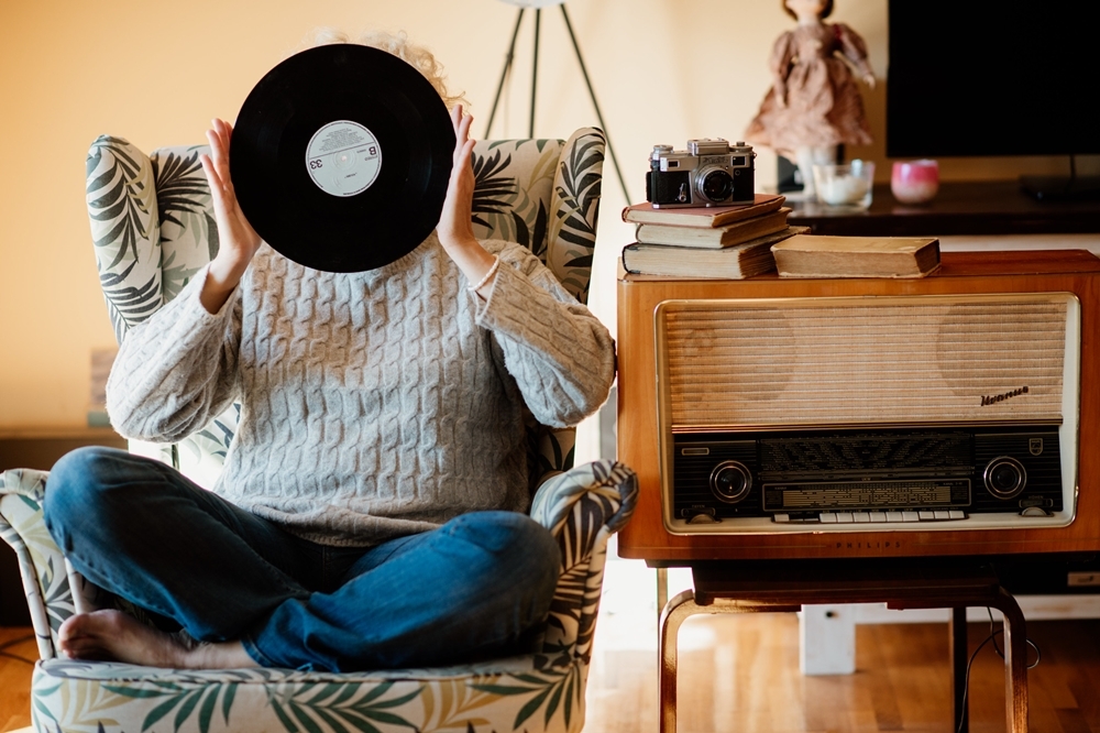 （2021 © Nenad Stojkovic , Anonymous woman sitting and holding a vinyl record in front of her head. @ Flickr, CC BY-SA 2.0.）