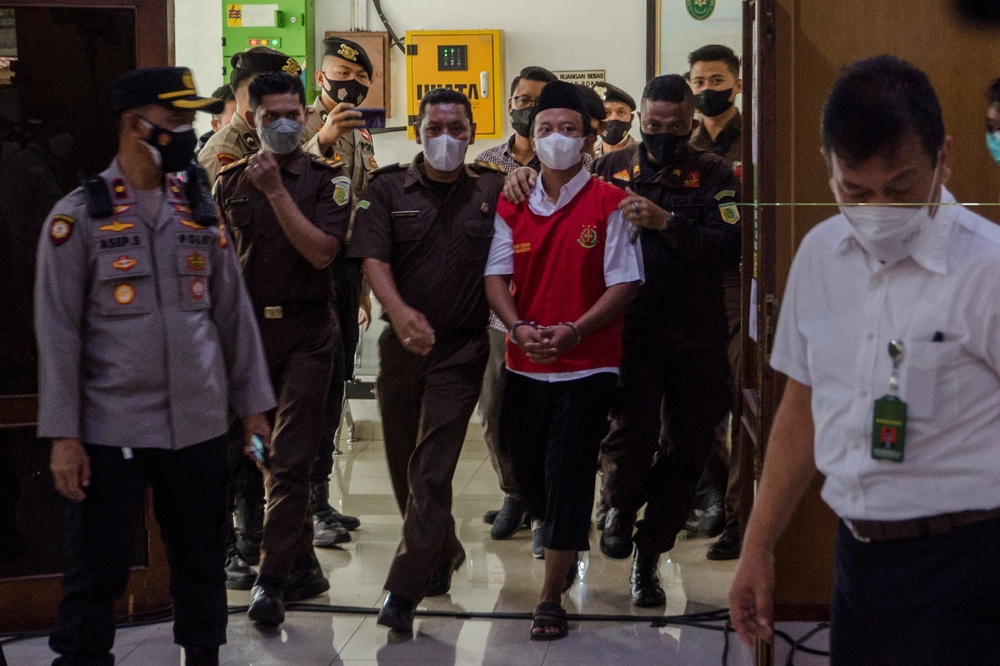 印尼「狼師」亨利（中間紅衣）被警察押解出庭聽審。（湯森路透）