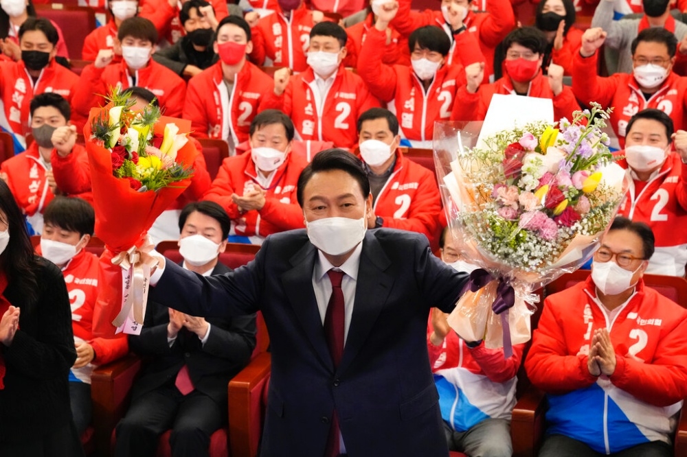 南韓最大在野黨國民力量候選人尹錫悅以48.56%的得票率，確定當選新任南韓總統。他手捧鮮花，接受同黨同志和支持者的祝賀。（美聯社）