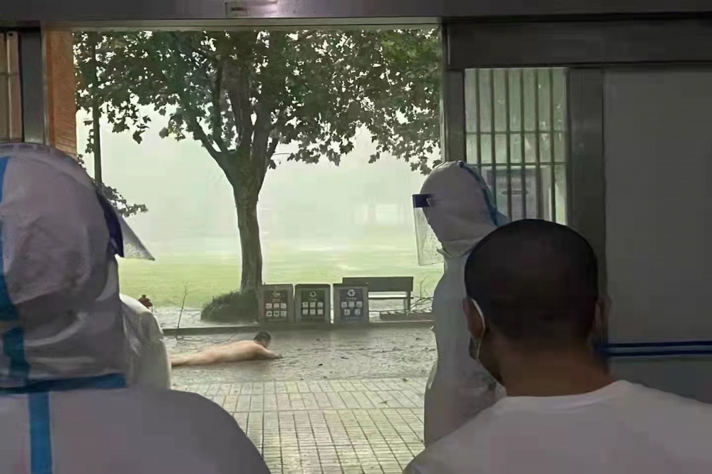 上海一名男子疑似因淋浴間被吹垮，全裸趴在馬路上等待協助。（擷取自推特）