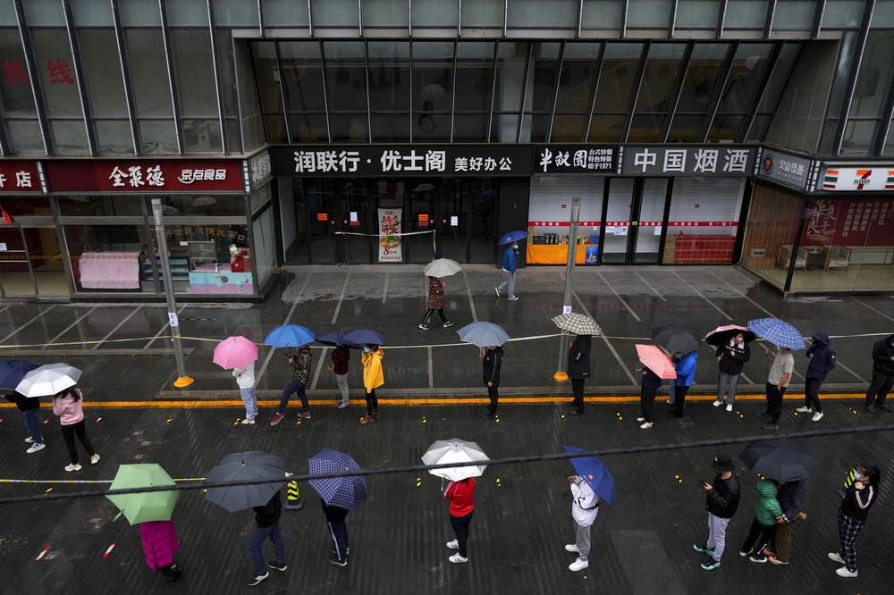 北京封城區域民眾冒雨等候做篩檢。（美聯社）