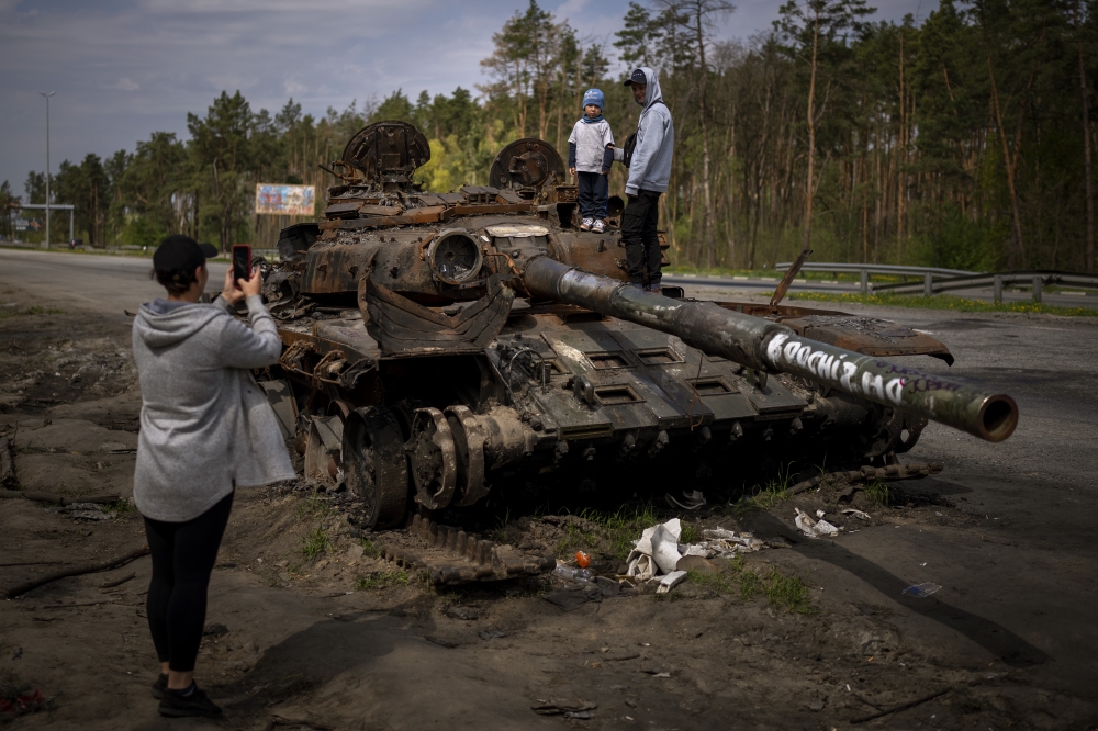 乌克兰民众在基辅近郊与被摧毁的俄国坦克合照。（美联社）(photo:UpMedia)