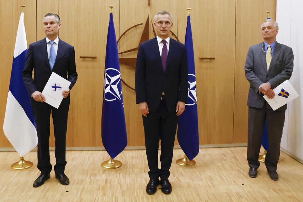 芬蘭大使（左）及瑞典大使（右）與北約秘書長史托騰伯格，共同出席兩國正式申請加入北約的儀式。（美聯社）