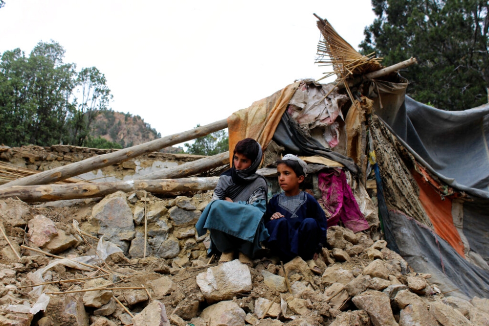 兩名阿富汗男童坐在他們被震毀的家。（美聯社）