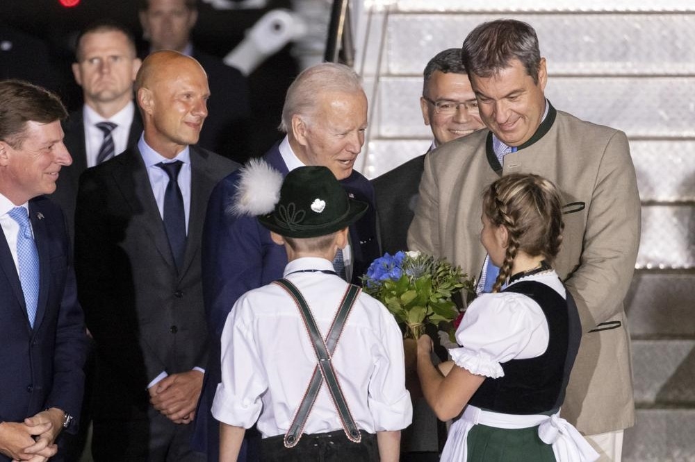 美國總統拜登抵達德國南部巴伐利亞地區，參加G7峰會。下機後接受穿著巴伐利亞傳統服飾的兒童獻花。（美聯社）