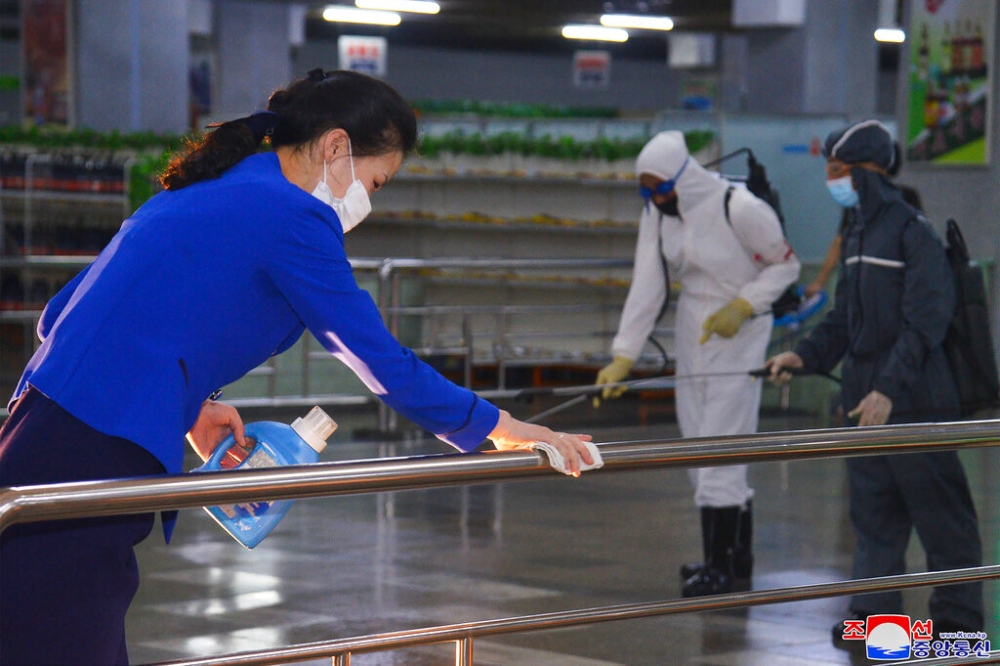 北韓商場職員進行消毒工作。（美聯社）