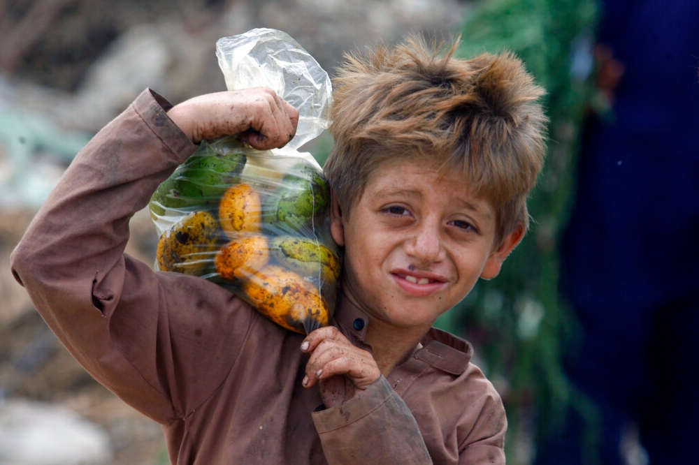 阿富汗難民男童拿著人道組織提供的芒果。（美聯社）