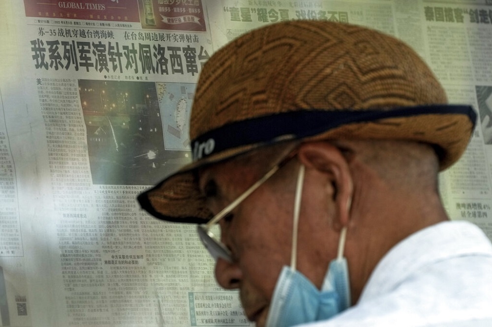 一位中國民眾站在北京街頭閱覽布告欄上的報紙，標題稱裴洛西的台灣之旅為「竄台」。（美聯社）