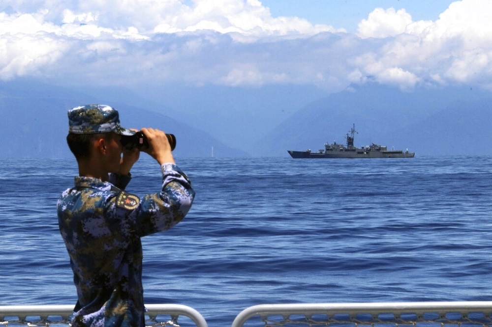 新華社5日釋出照片，呈現一名軍人用望遠鏡遠眺台灣的蘭陽號巡防艦。（美聯社）