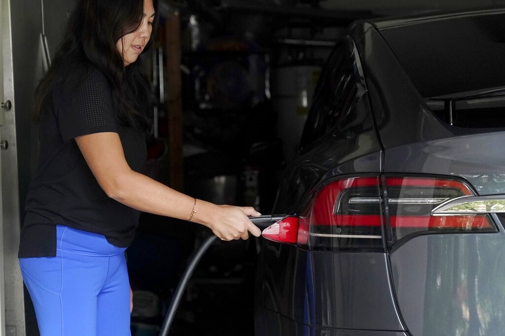 舊金山一 名女子替特斯拉電動車充電。（美聯社）