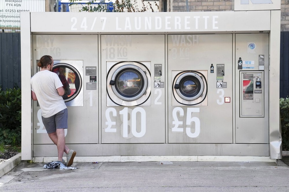 英國一家自助洗衣店標示價格調漲。英國今年能源價格大漲。（美聯社）