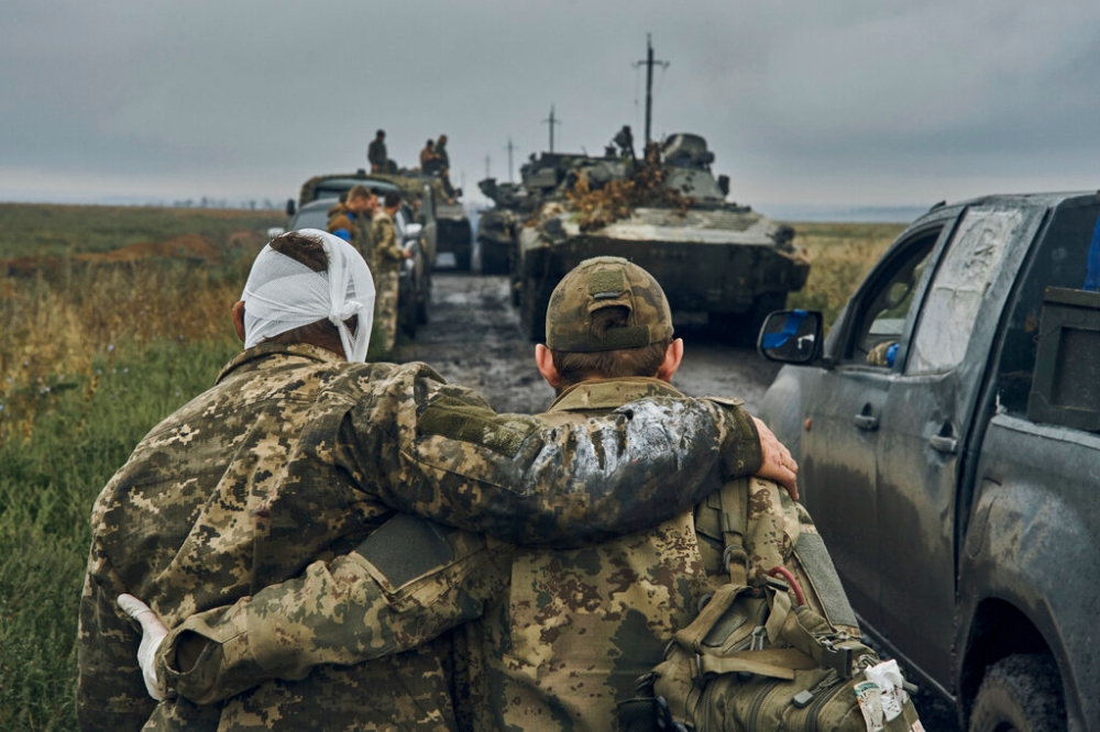 烏克蘭軍車開進哈爾科夫奪回失土，一名烏克蘭士兵協助攙扶受傷同袍。（美聯社）