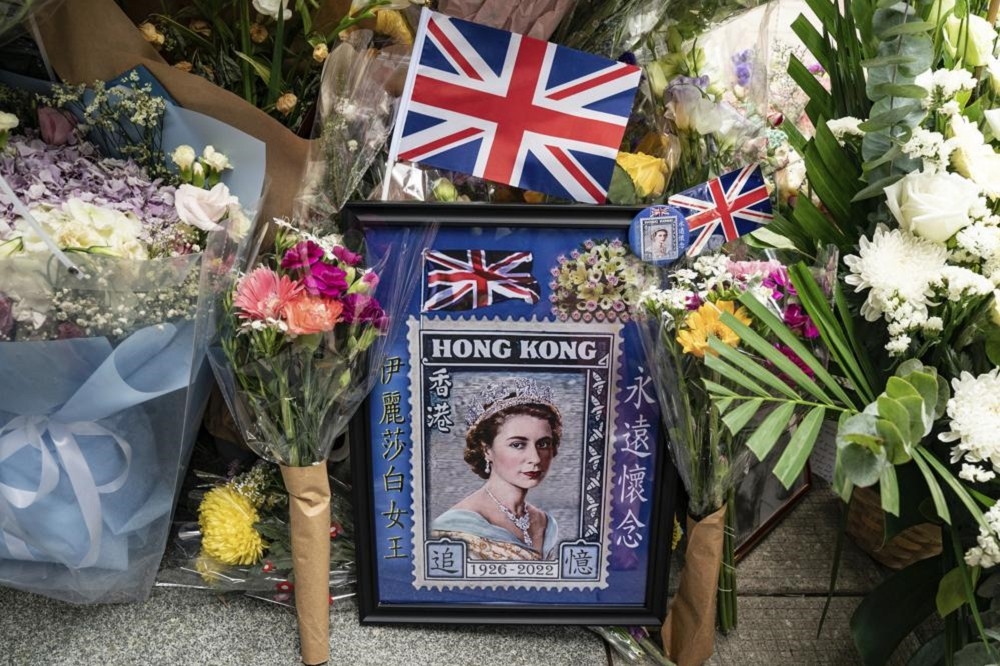 英國女王過世，許多香港人自然湧現悲懷，頂著太陽排隊四小時，到英國領事館擺花吊唁。（美聯社）