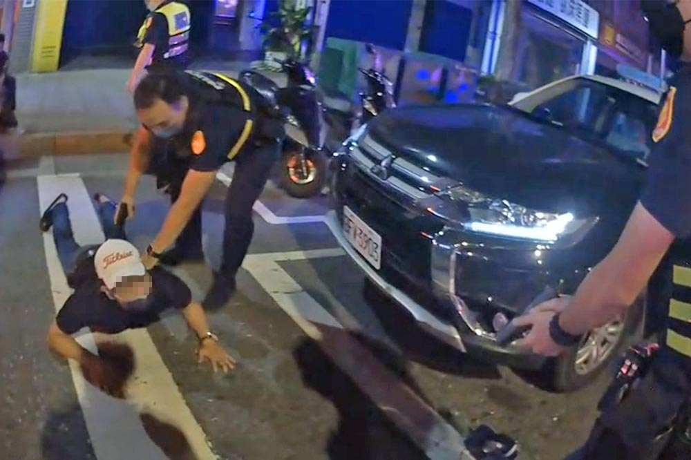 北市21日深夜驚傳一起槍案，戴著白帽的范姓嫌犯遭警方壓制在地逮捕。（翻攝畫面）