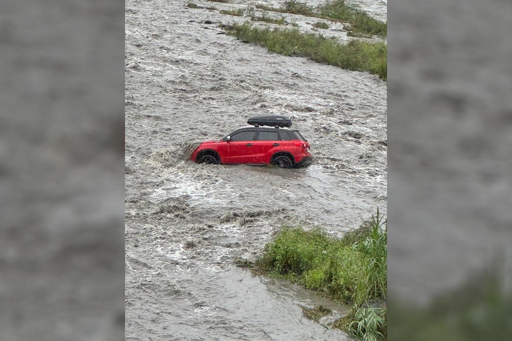 宜蘭清水地熱公園旁的清水溪因大雨暴漲，在溪床露營的民眾受困，其中1輛車被卡溪床。（取自記者爆料網）