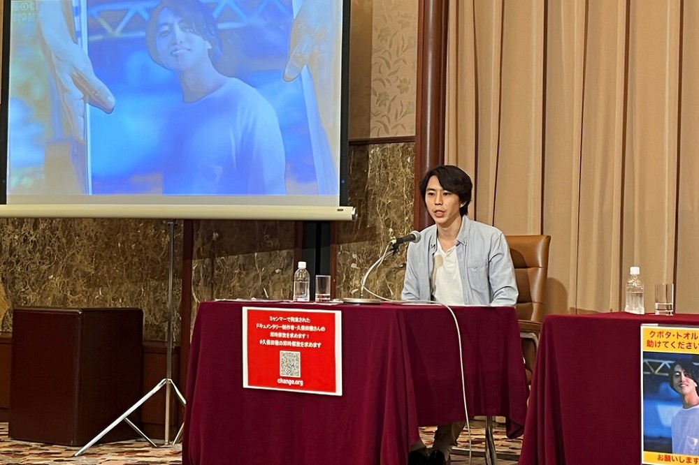 日本記者同業在東京聲援在緬甸被捕的久保田徹，螢幕上出現久保的影像。（美聯社）
