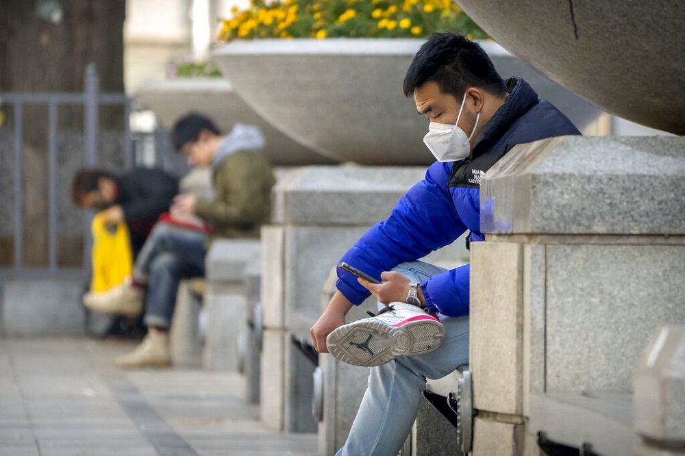 北京王府井，民眾戴著口罩坐在路邊。（美聯社）