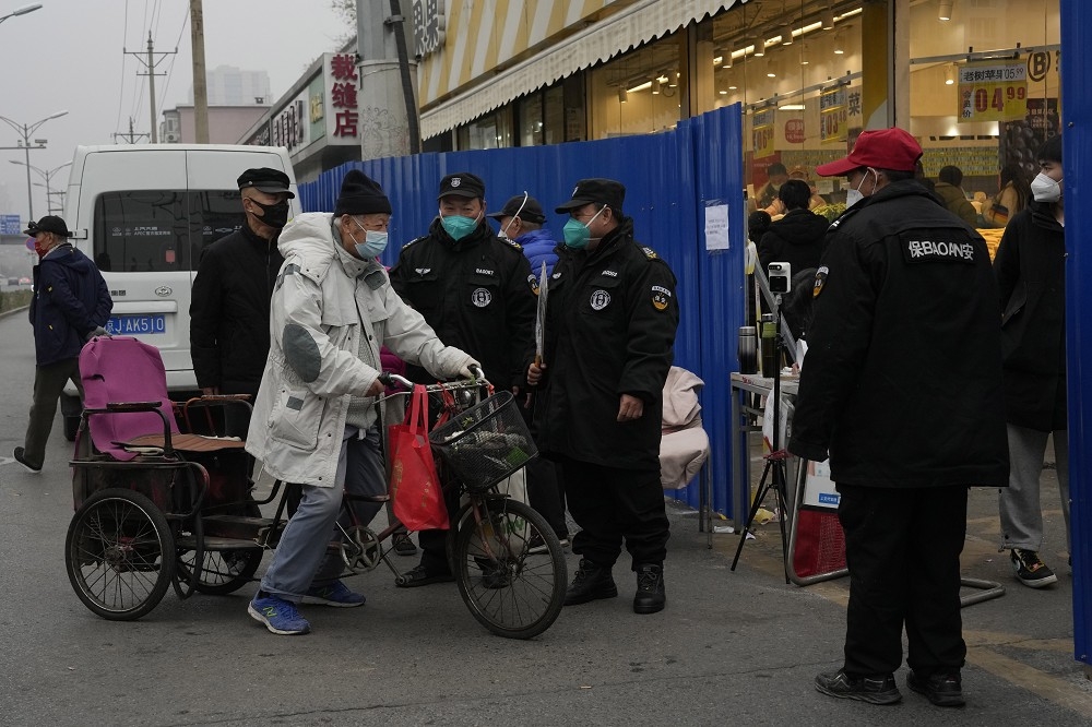 北京某社區保全人員24日在門口檢查出入民眾。（美聯社）