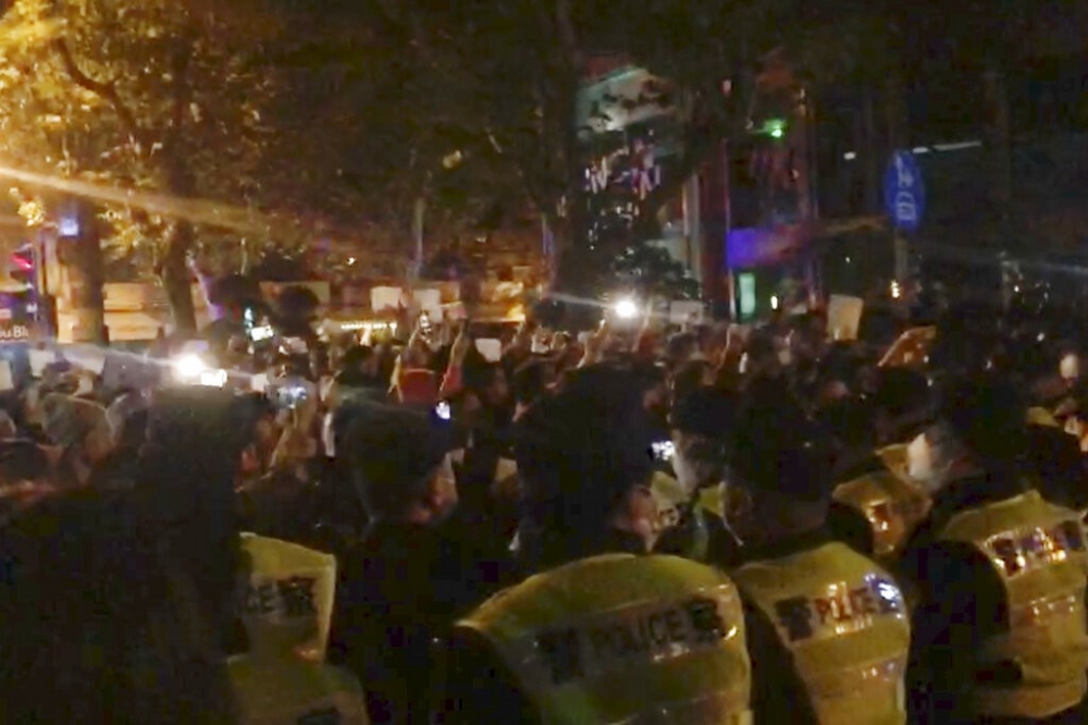 上海26日晚民眾聚集哀悼新疆烏魯木齊因封控延誤救人的悲劇，激憤民眾與警方對峙。（美聯社）