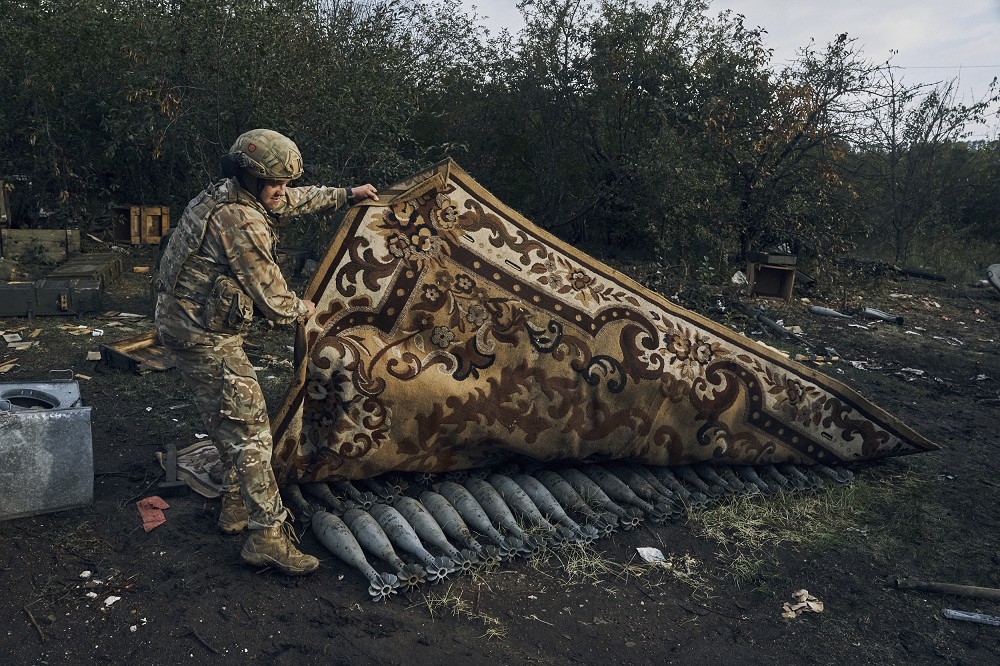 一名烏克蘭士兵正在檢視俄軍撤退後遺留在陣地內的彈藥。（美聯社）