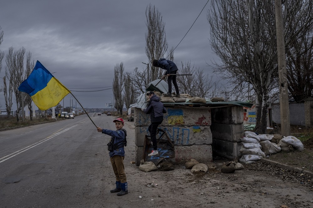 烏克蘭官員指控俄軍曾在赫爾松地區進行虐童，圖為1名男孩在赫爾松收復後揮舞烏克蘭國旗。（美聯社）