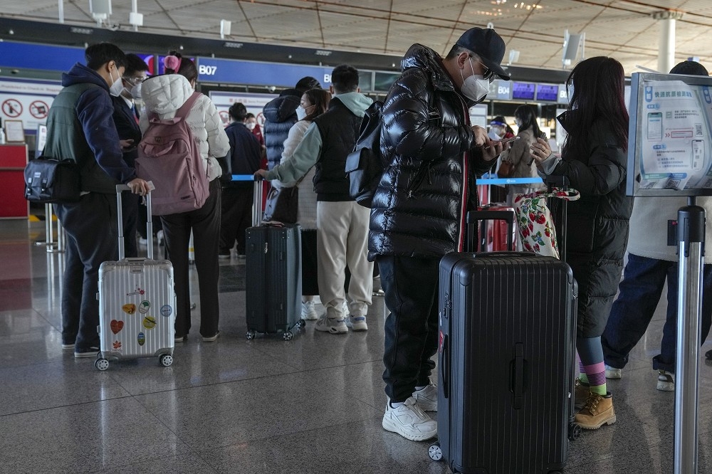中國民眾在北京國際機場填寫健康報表，準備搭機出國。（美聯社）