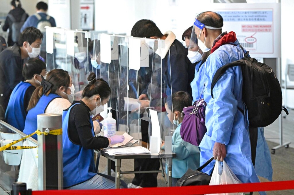 圖為從上海入境的旅客抵達日本成田機場時出示新冠陰性證明。（資料照片／美聯社）