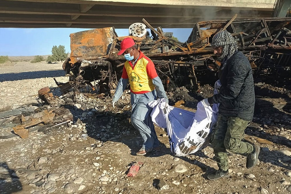 俾路支省救難人員在巴士墜橋現場，搬離罹難者遺體。（美聯社）